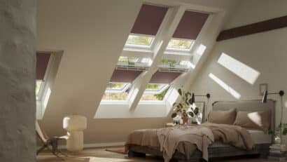 Chambre mansardée avec plafond en pente et fenêtres de toit VELUX, confortable et lumineuse.