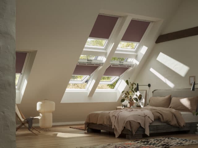Chambre mansardée avec plafond en pente et fenêtres de toit VELUX, confortable et lumineuse.