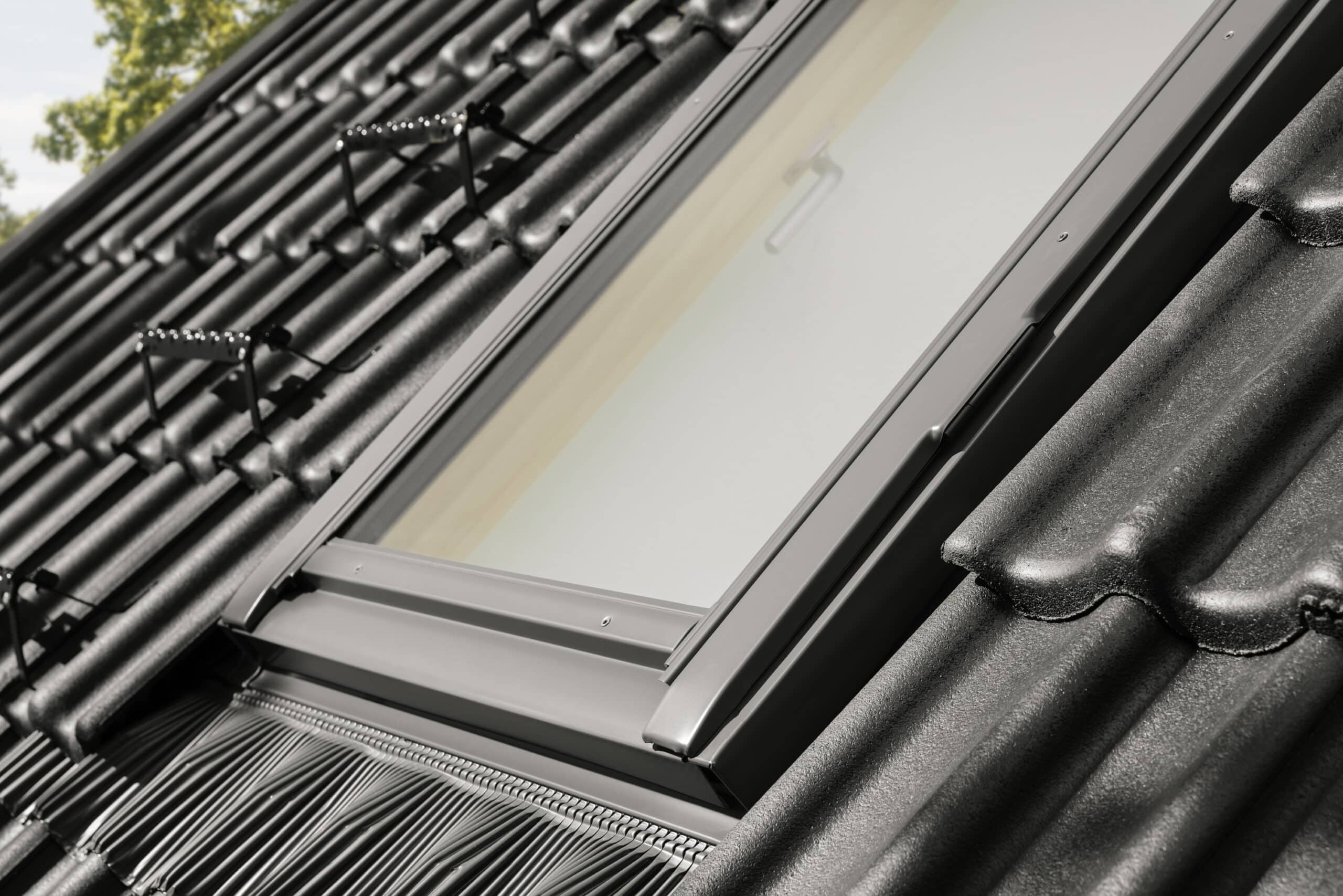 Toiture en tuiles noires avec fen&ecirc;tre de toit VELUX ferm&eacute;e.