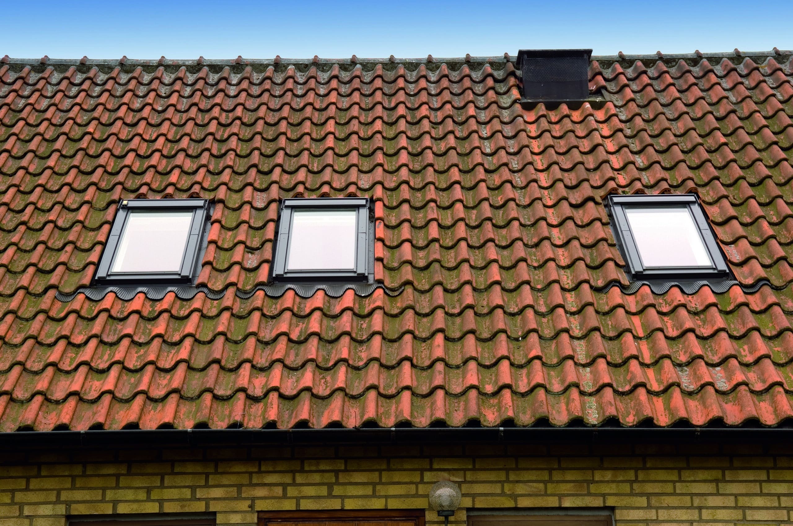 Toiture en tuiles rouges avec trois fen&ecirc;tres de toit VELUX, design traditionnel.