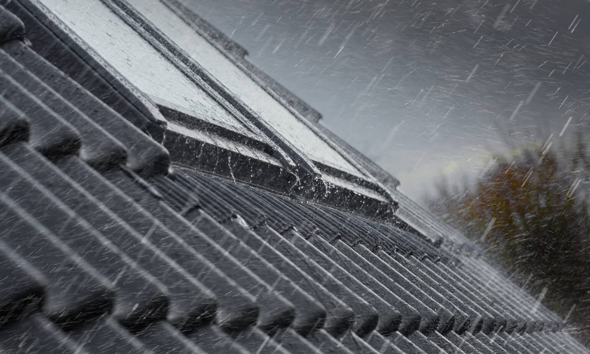 Toiture en tuiles avec fenêtres de toit VELUX fermées pendant les fortes pluies.