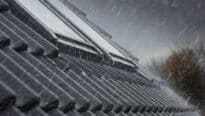 Toiture en tuiles avec fenêtres de toit VELUX fermées pendant les fortes pluies.