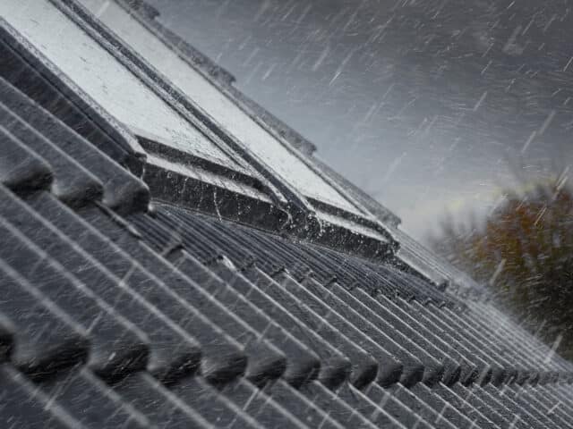Toiture en tuiles avec fenêtres de toit VELUX fermées pendant les fortes pluies.