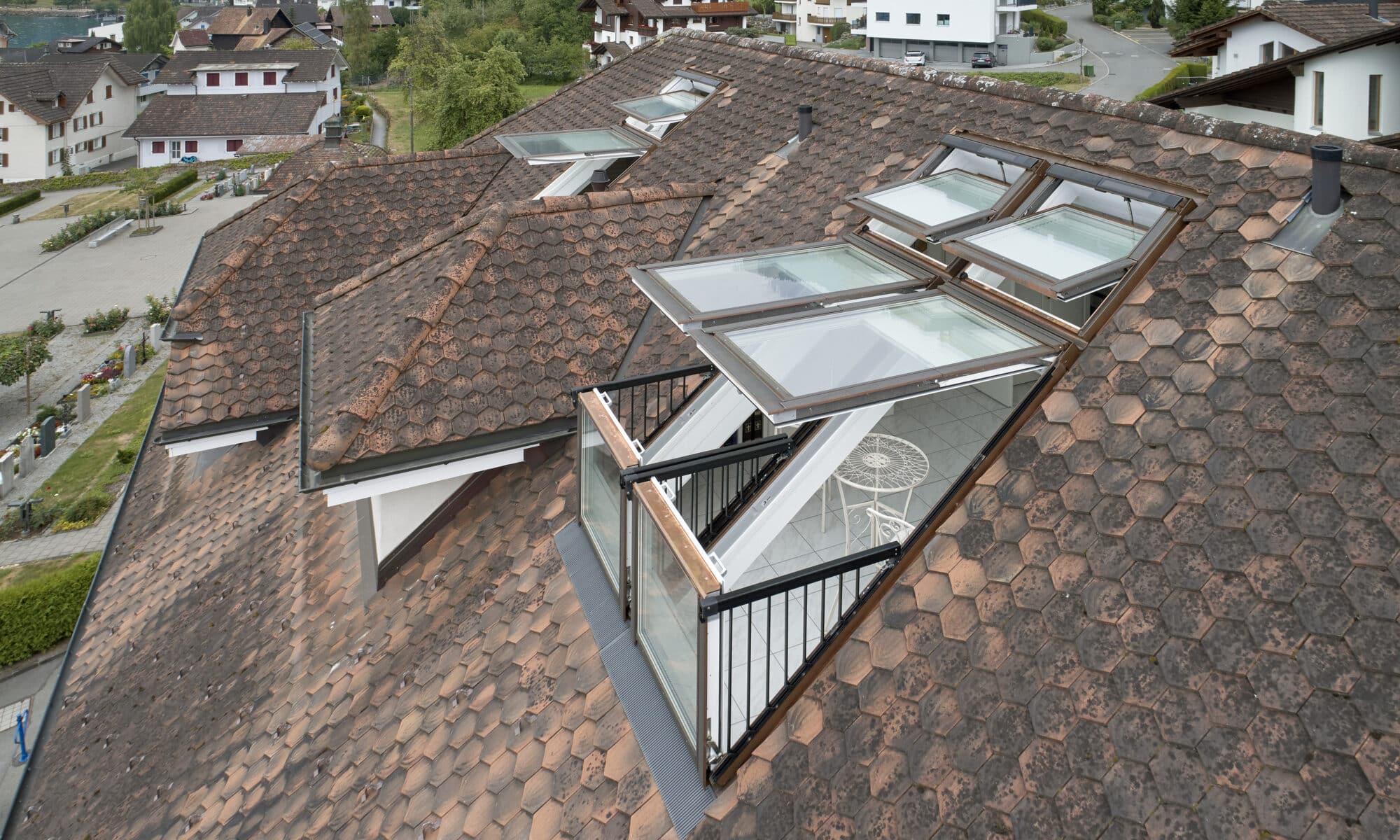 Fenêtres de toit VELUX sur un toit en tuiles, révélant un balcon.