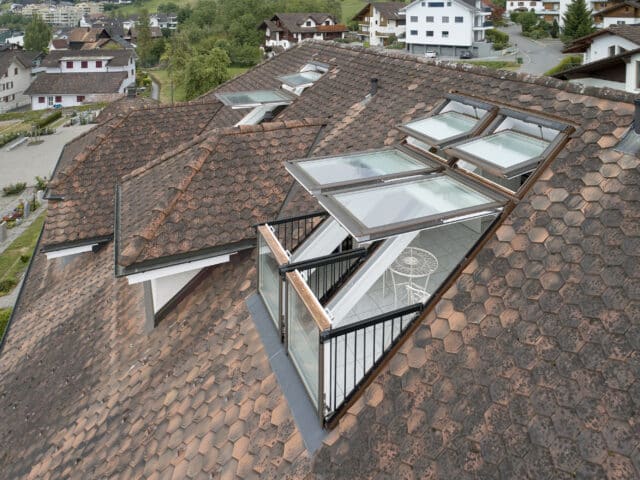 Fenêtres de toit VELUX sur un toit en tuiles, révélant un balcon.