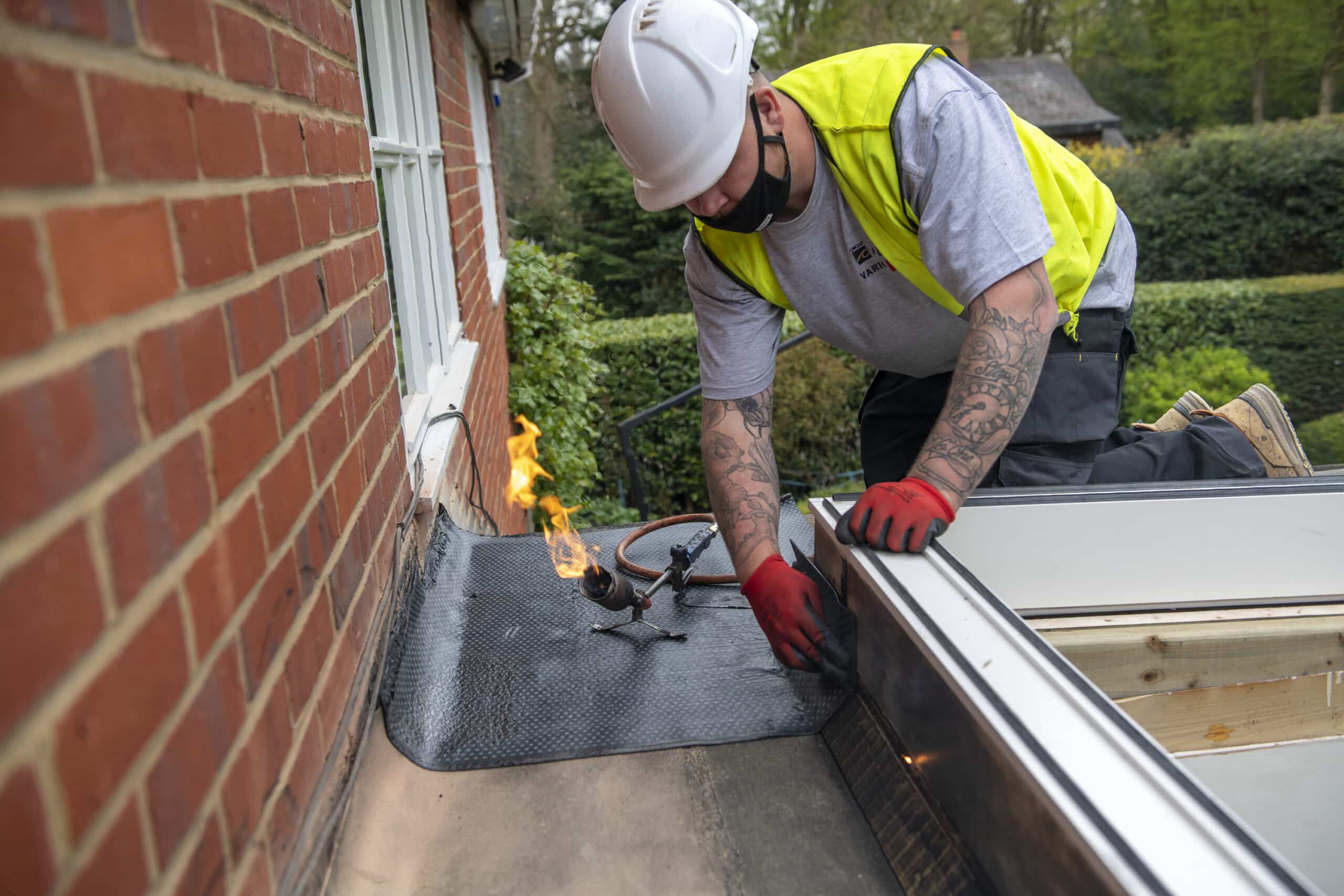 Ouvrier posant du feutre bitum&eacute; sur un toit plat &agrave; l'aide d'un chalumeau.