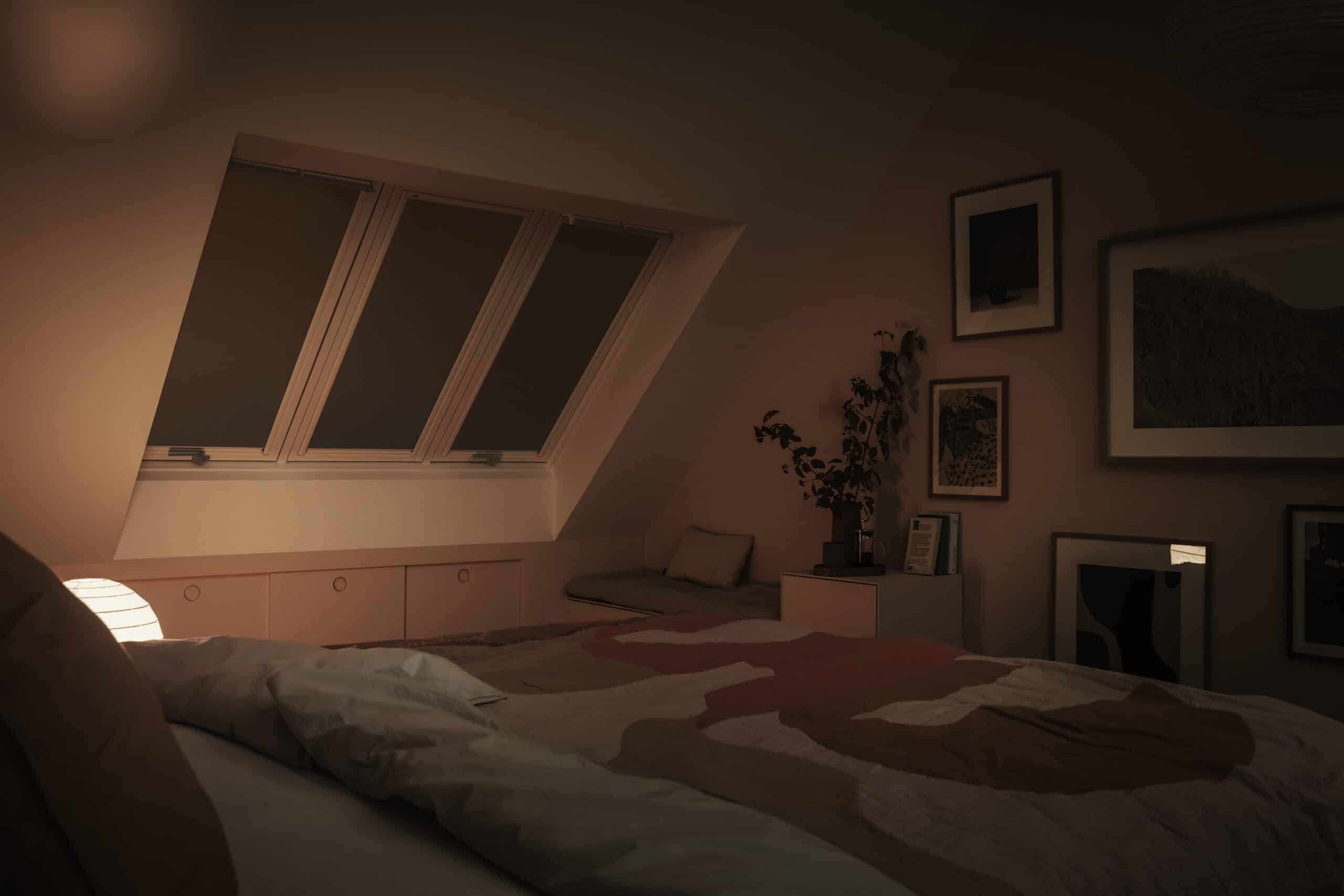 Chambre mansard&eacute;e avec plafond en pente et fen&ecirc;tre de toit VELUX ferm&eacute;e, ambiance chaleureuse.