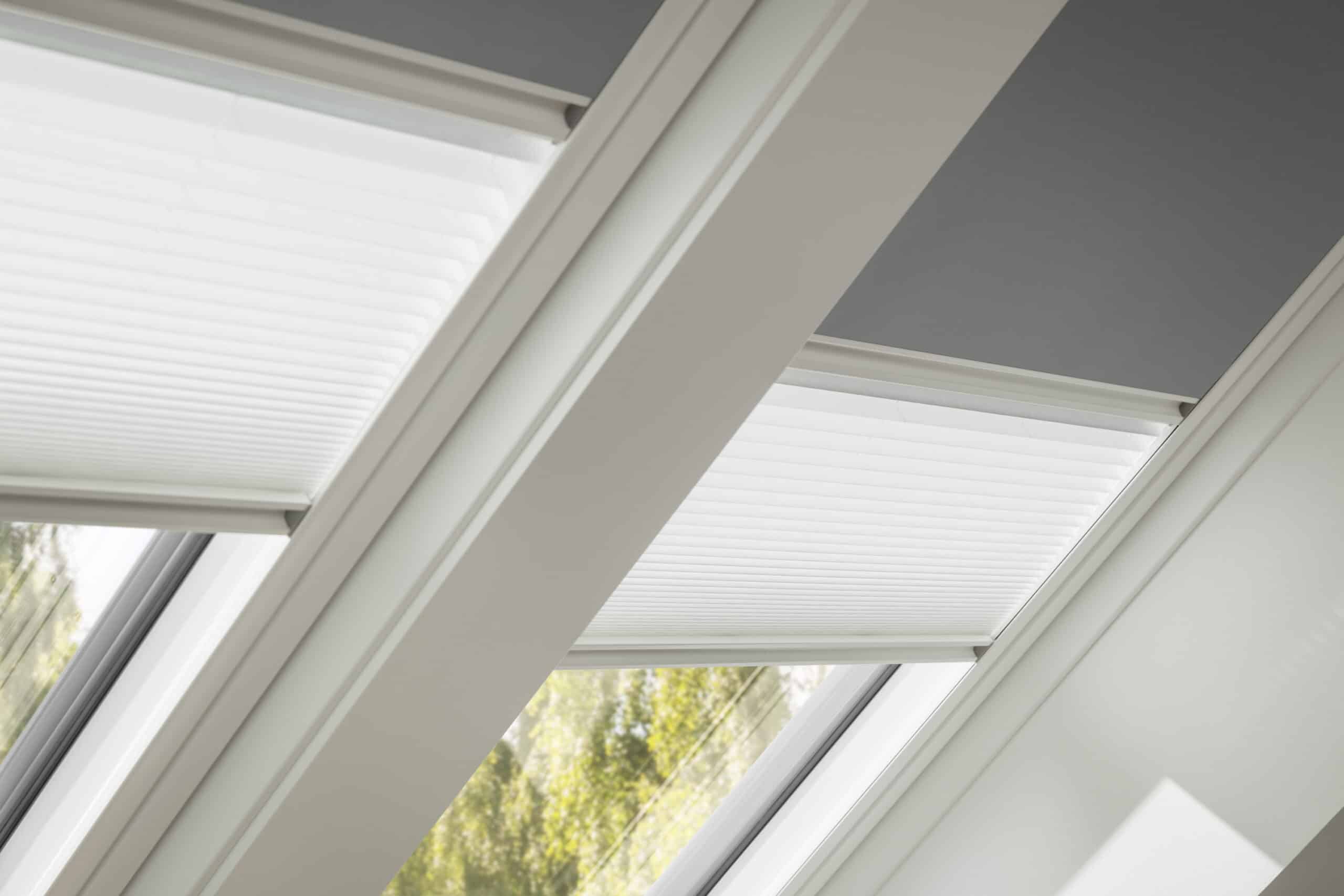 Fen&ecirc;tre de toit VELUX avec stores ferm&eacute;s, int&eacute;gr&eacute;e dans un plafond inclin&eacute;.