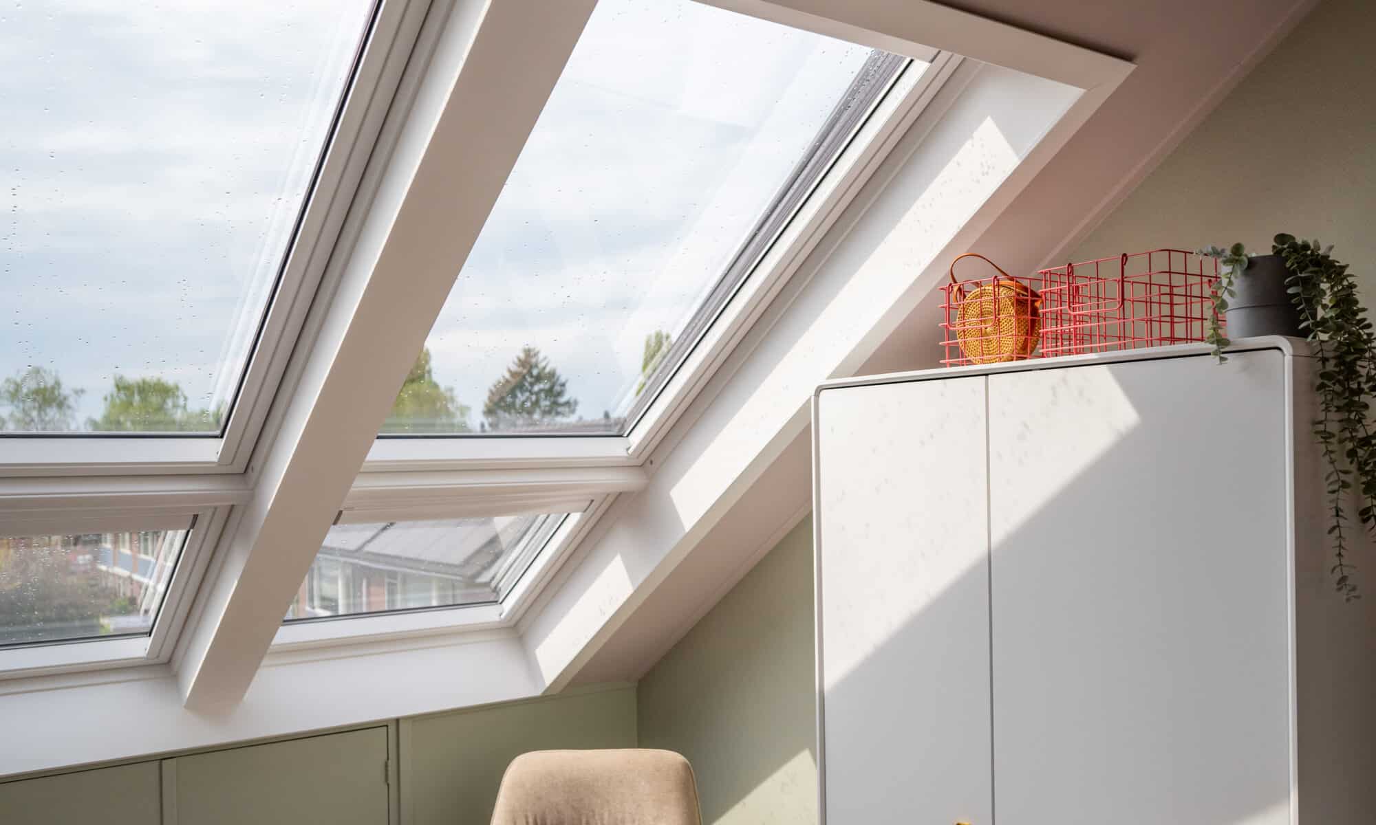 Chambre mansardée avec fenêtres de toit VELUX, plafond mansardé et décoration chaleureuse.