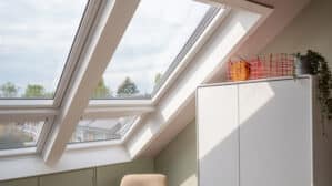 Chambre mansardée avec fenêtres de toit VELUX, plafond mansardé et décoration chaleureuse.