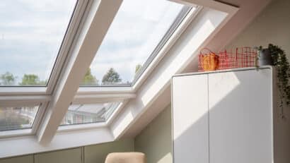 Chambre mansardée avec fenêtres de toit VELUX, plafond mansardé et décoration chaleureuse.