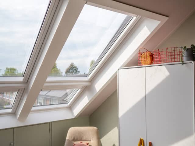 Chambre mansardée avec fenêtres de toit VELUX, plafond mansardé et décoration chaleureuse.