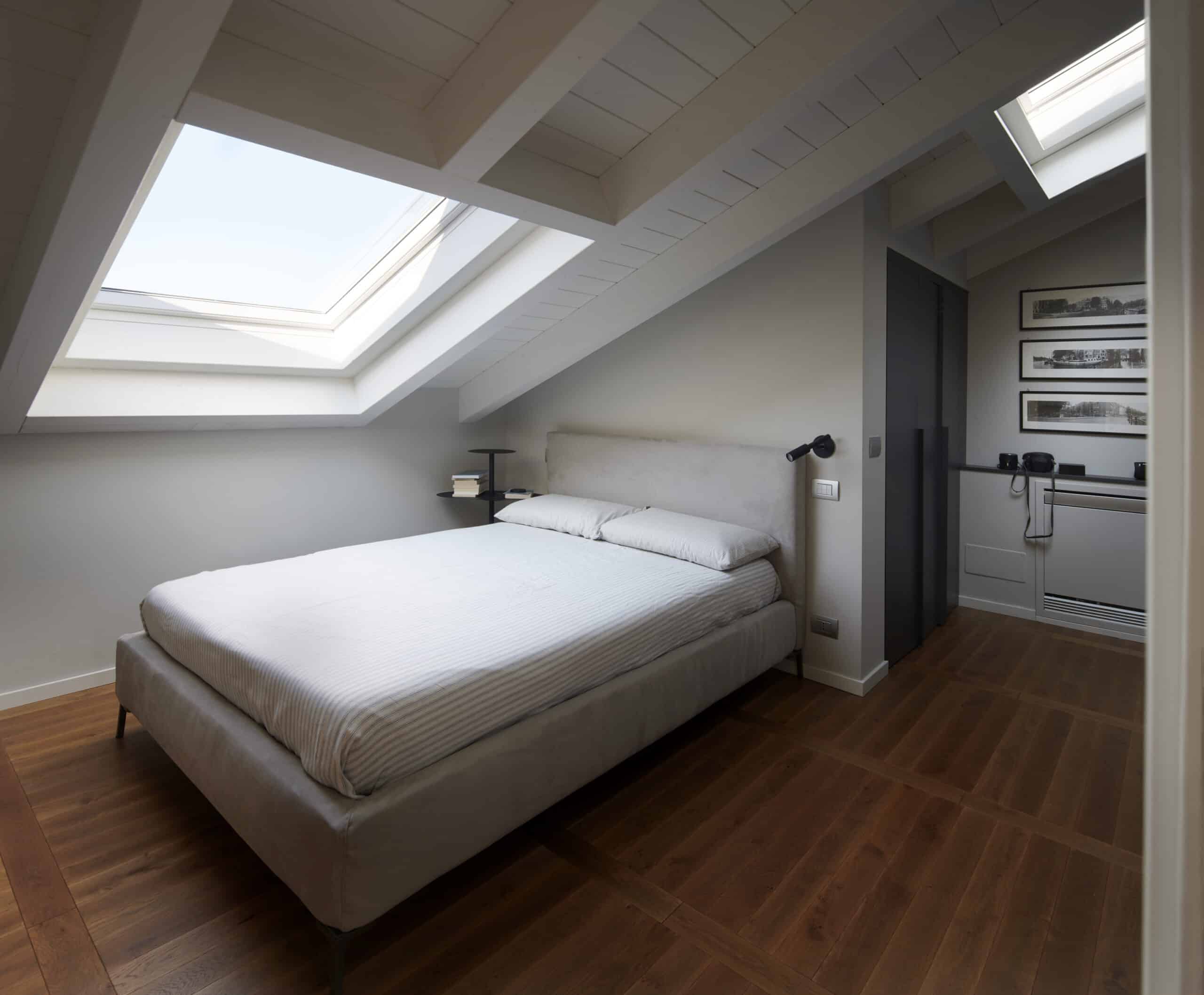 Chambre mansardée avec plafond en pente et fenêtres de toit VELUX, laissant entrer la lumière naturelle.