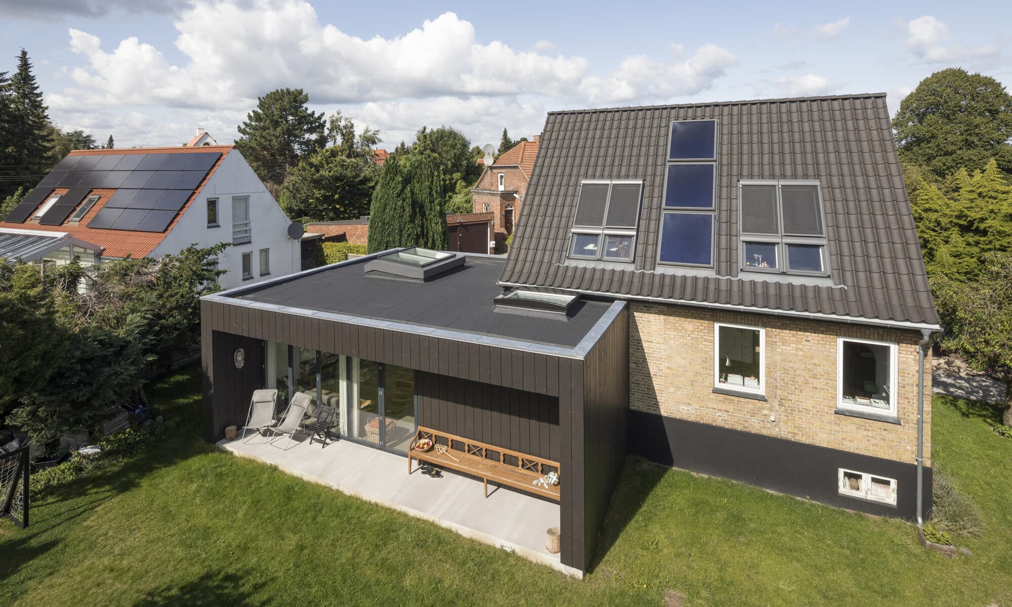 Maison moderne avec panneaux solaires et extension à toit plat.
