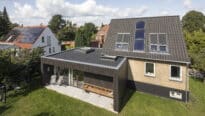 Maison moderne avec panneaux solaires et extension à toit plat.