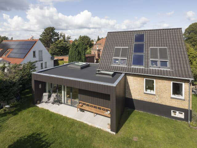 Maison moderne avec panneaux solaires et extension à toit plat.