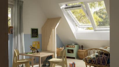 Chambre d'enfant mansardée avec plafond en pente et fenêtre de toit VELUX, remplie de jouets.