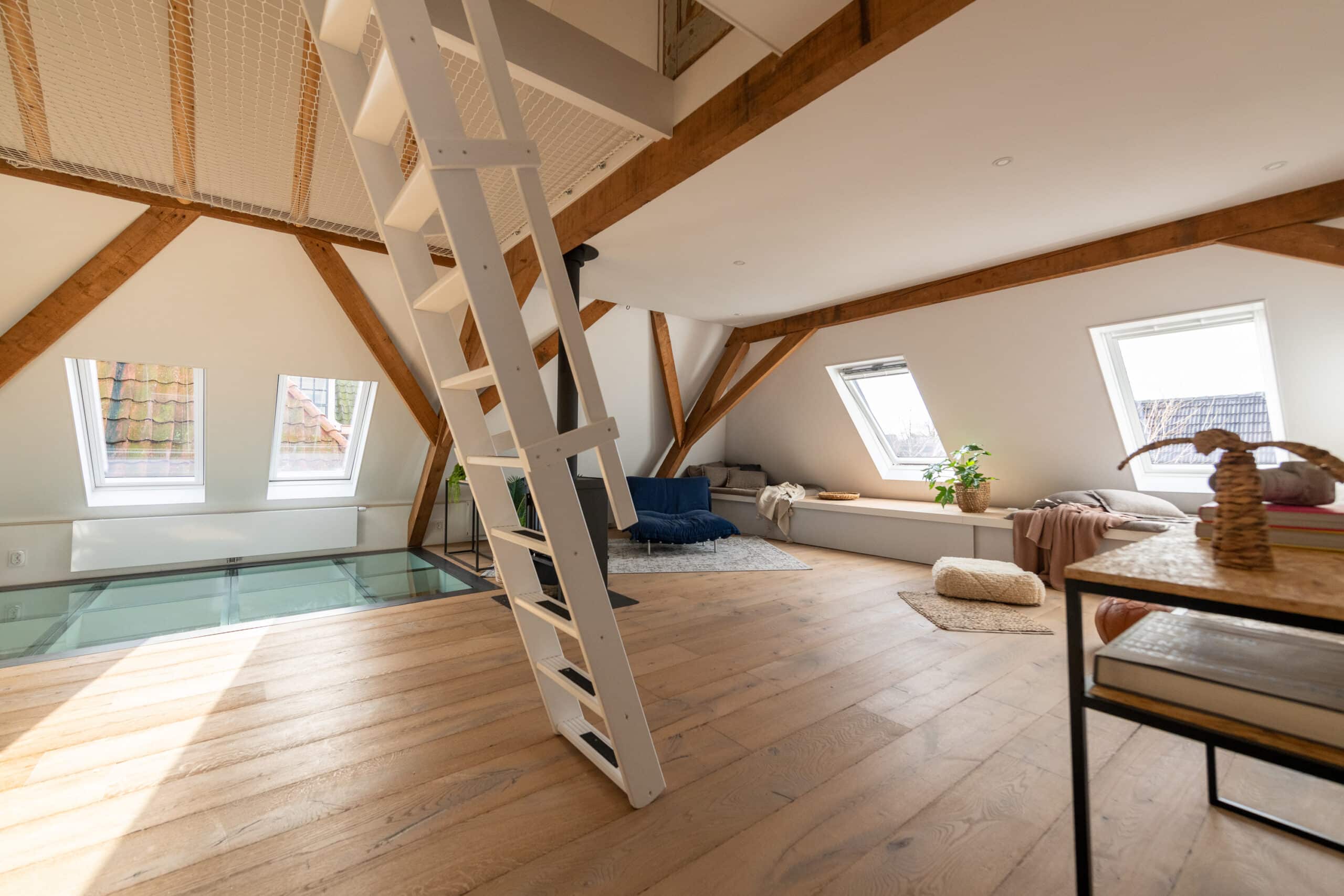 Pi&egrave;ce mansard&eacute;e avec plafond en pente, fen&ecirc;tres VELUX et charpente en bois.
