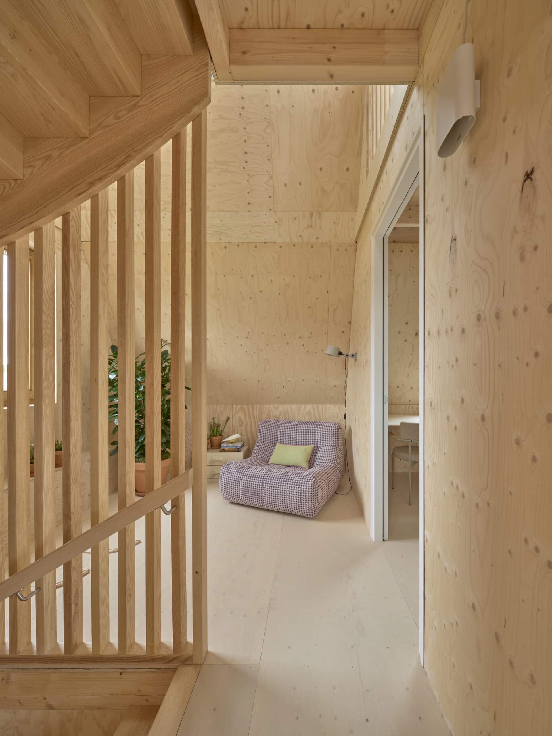 Palier mansardé avec murs en tasseaux de bois et coin salon confortable.