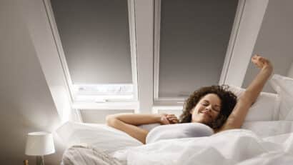 Chambre mansardée avec plafond en pente et fenêtre de toit VELUX, literie confortable.
