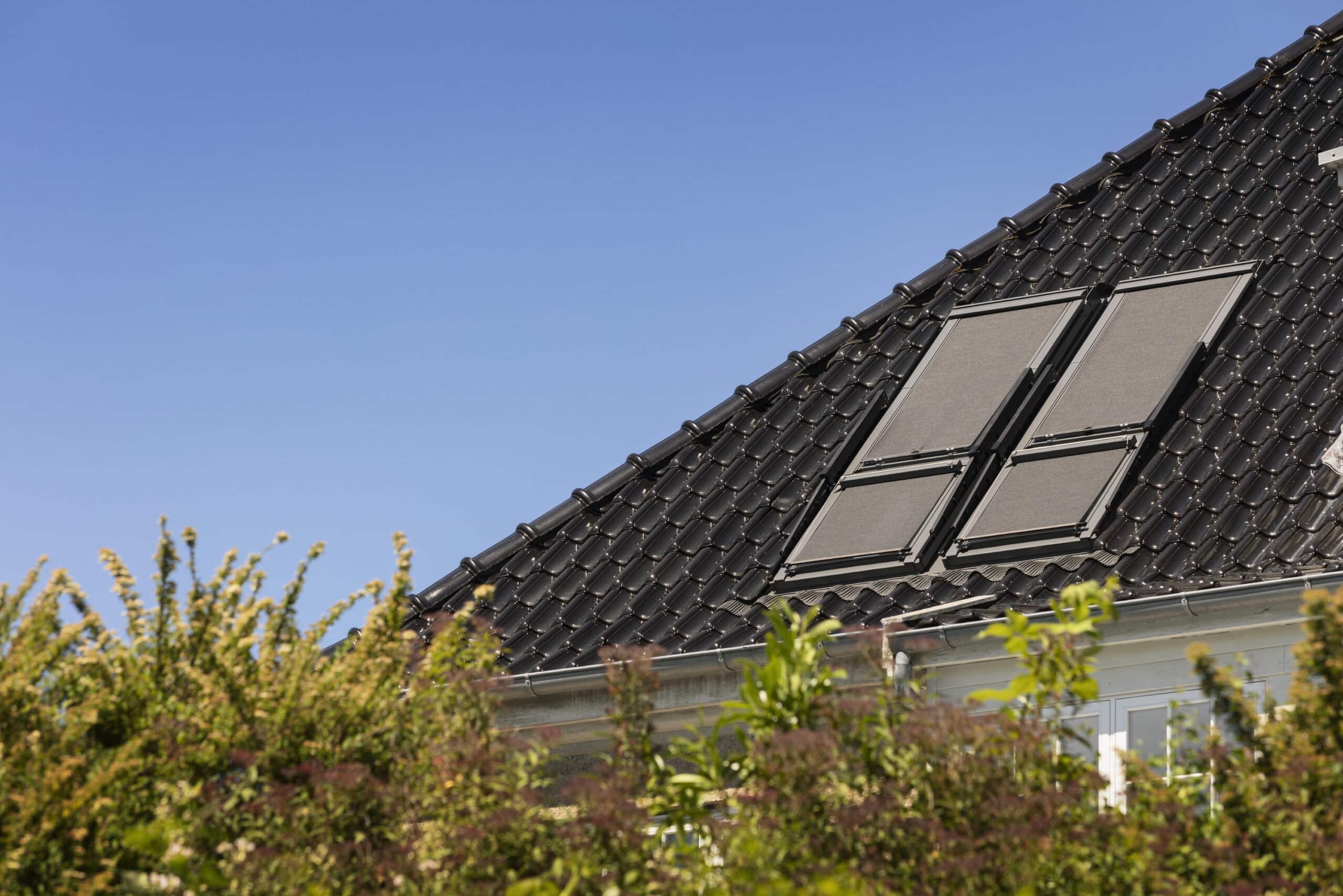 Toiture en tuiles noires avec panneaux solaires intégrés sur un bâtiment résidentiel.
