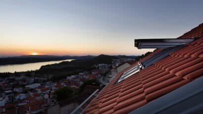 Vue depuis le toit avec les fenêtres de toit VELUX ouvertes au coucher du soleil.