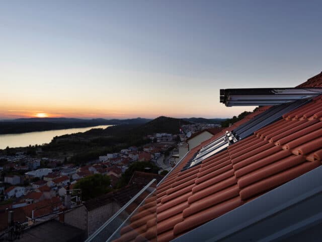Vue depuis le toit avec les fenêtres de toit VELUX ouvertes au coucher du soleil.