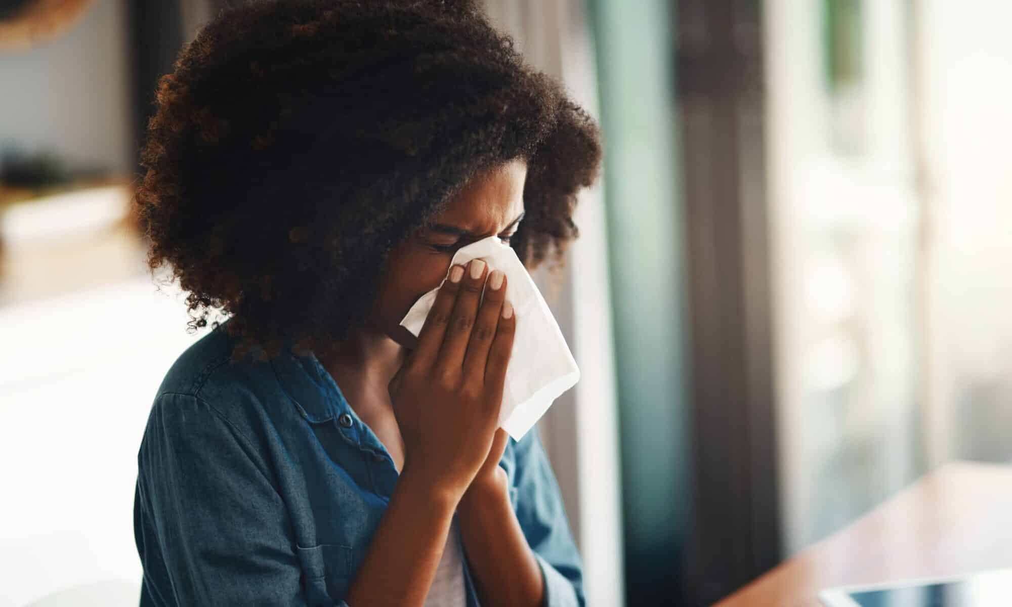 femme qui éternue à l'intérieur en raison d'allergie au pollen de printemps.