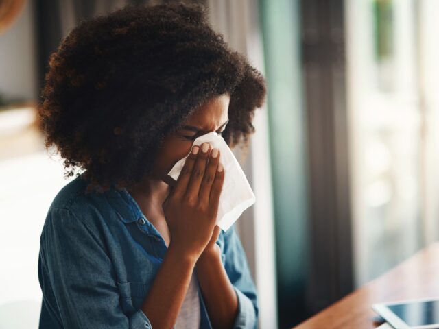 femme qui éternue à l'intérieur en raison d'allergie au pollen de printemps.