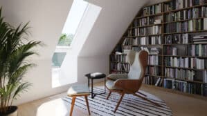 Coin lecture sous les combles avec fenêtre de toit VELUX et bibliothèque remplie de livres.