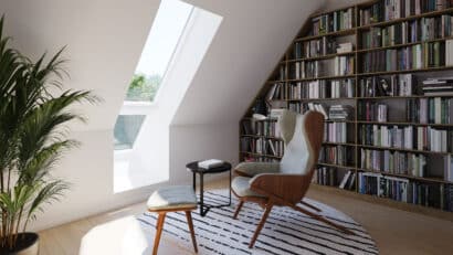 Coin lecture sous les combles avec fenêtre de toit VELUX et bibliothèque remplie de livres.