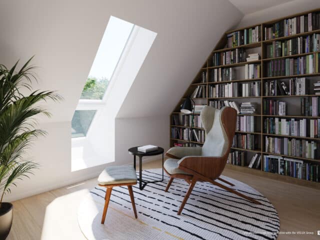 Coin lecture sous les combles avec fenêtre de toit VELUX et bibliothèque remplie de livres.