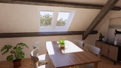 Coin repas sous les combles avec plafond en pente, charpente apparente et fenêtres de toit VELUX.