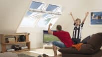 Pièce mansardée avec plafond mansardé, fenêtres de toit VELUX et coin salon