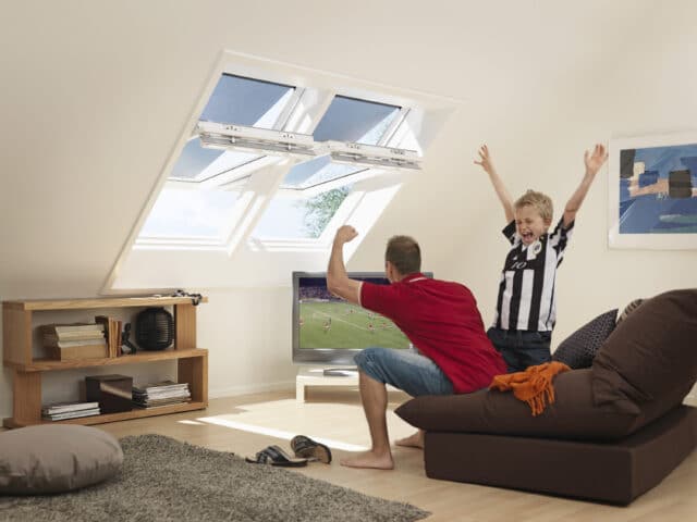 Pièce mansardée avec plafond mansardé, fenêtres de toit VELUX et coin salon
