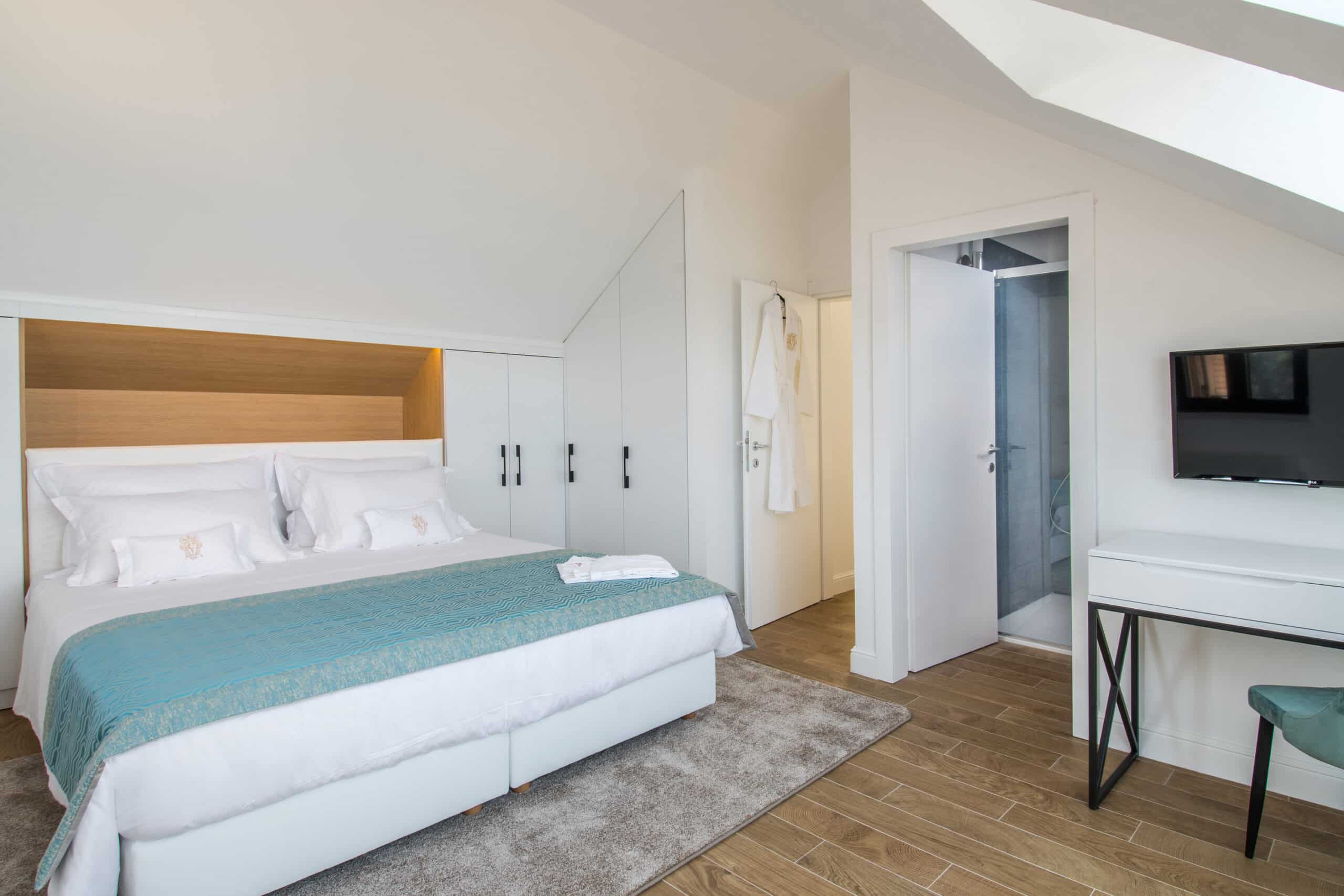 Chambre mansardée avec plafond en pente et fenêtre de toit VELUX, mobilier moderne.