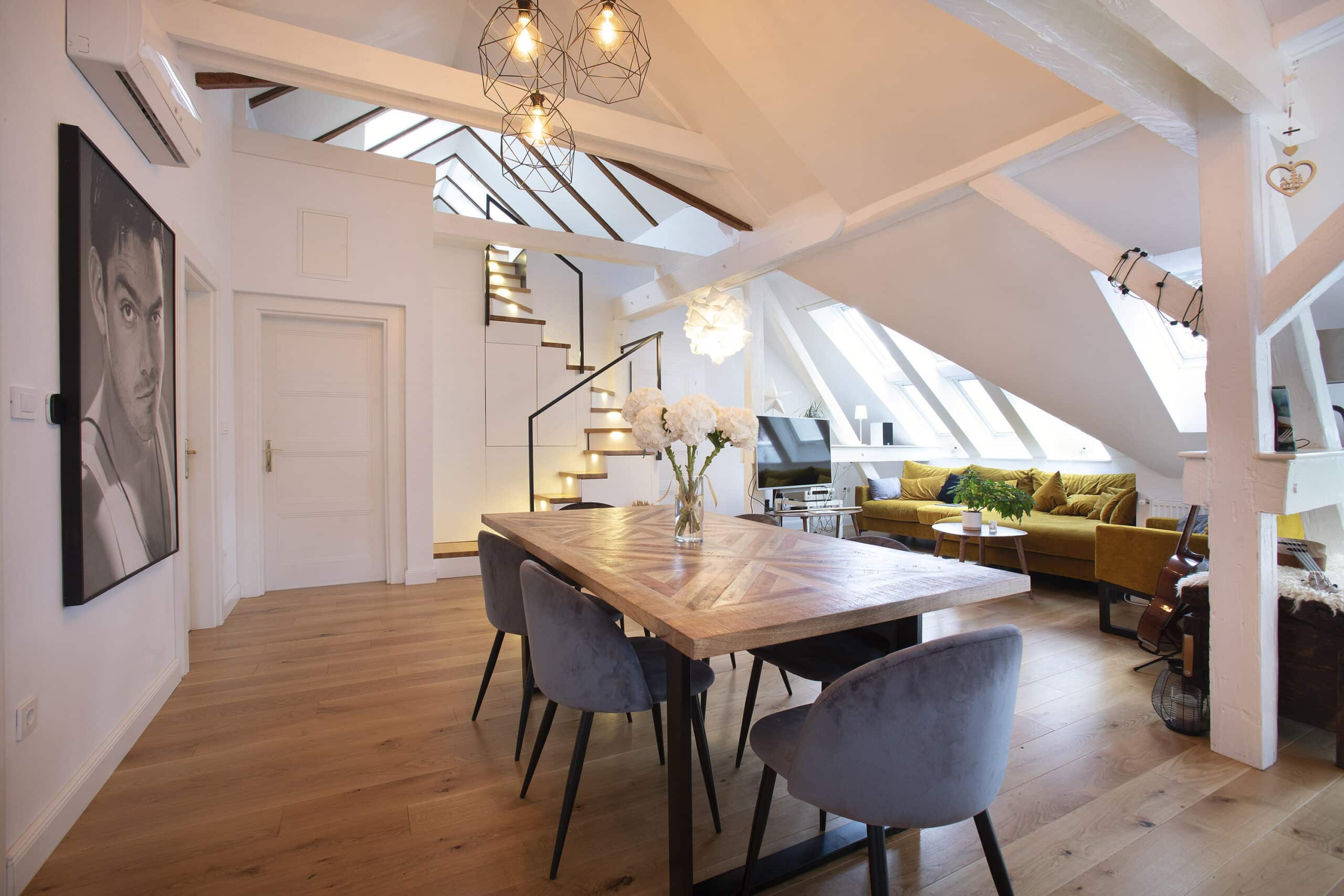 Espace de vie sous combles avec plafond en pente, fen&ecirc;tres de toit VELUX et mobilier moderne.
