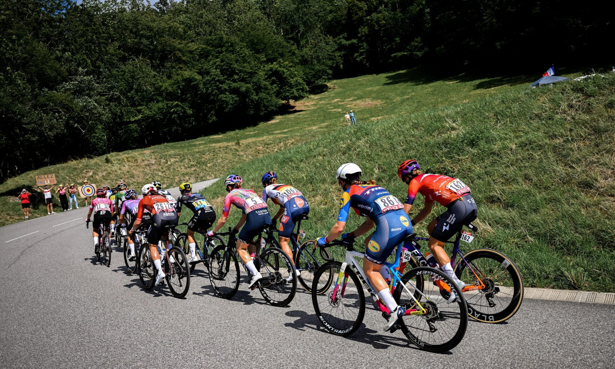 Des cyclistes qui gravissent une côte sur une route sinueuse, sous les acclamations des spectateurs.