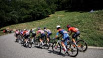 Des cyclistes qui gravissent une côte sur une route sinueuse, sous les acclamations des spectateurs.