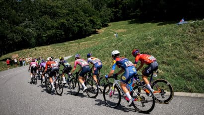 Des cyclistes qui gravissent une côte sur une route sinueuse, sous les acclamations des spectateurs.