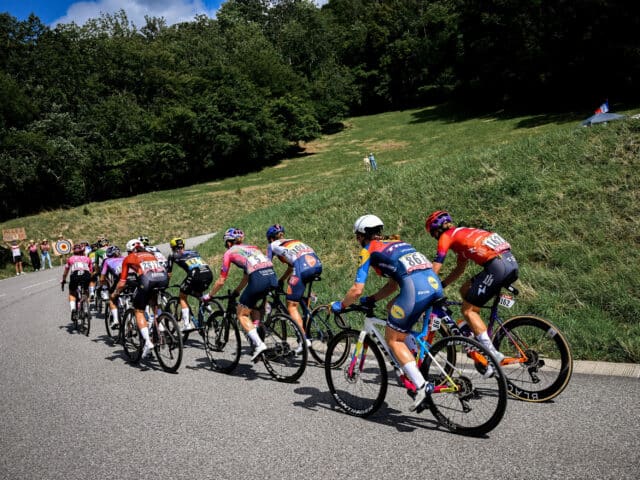 Des cyclistes qui gravissent une côte sur une route sinueuse, sous les acclamations des spectateurs.