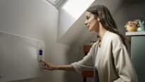 Chambre sous les combles avec plafond en pente et fenêtre de toit VELUX, personne réglant un panneau chauffant