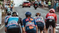 Des cyclistes femmes qui gravissent la côte à toute vitesse, vêtus de maillots colorés et coiffés de casques.