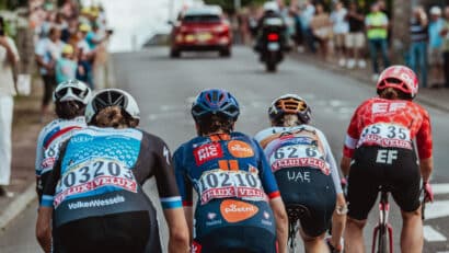 Des cyclistes femmes qui gravissent la côte à toute vitesse, vêtus de maillots colorés et coiffés de casques.