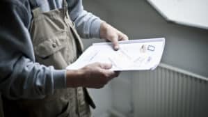 Un ouvrier du bâtiment examine des plans architecturaux près d'une fenêtre de toit VELUX fermée.