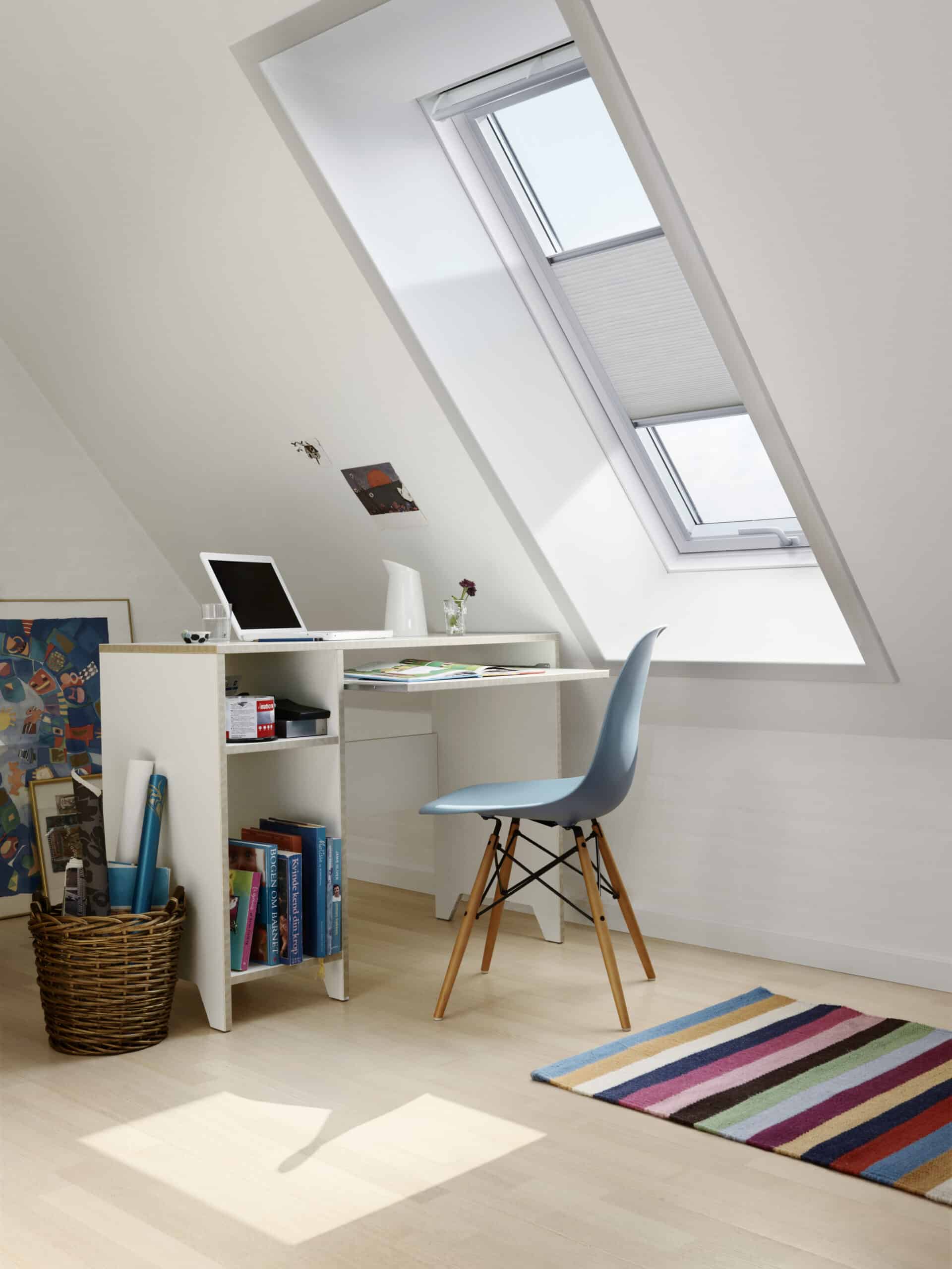 Espace de travail sous combles avec plafond en pente et fen&ecirc;tre de toit VELUX, am&eacute;nag&eacute; avec un bureau et une chaise.