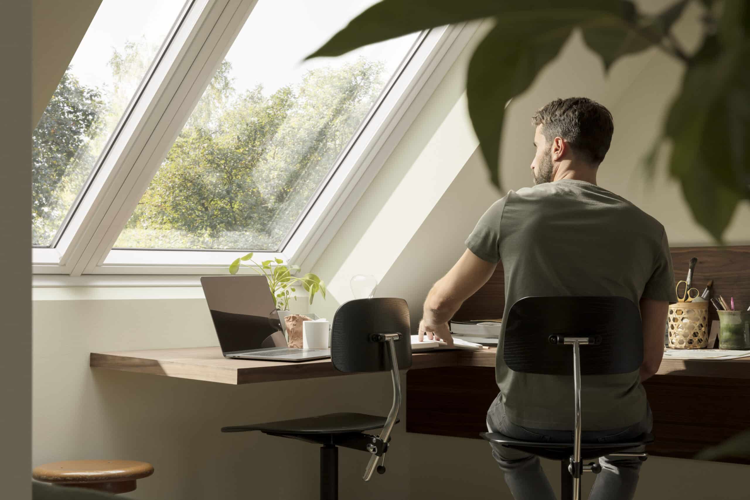 Espace de travail dans le grenier avec plafond incliné et fenêtre de toit en VELUX, lumière naturelle.