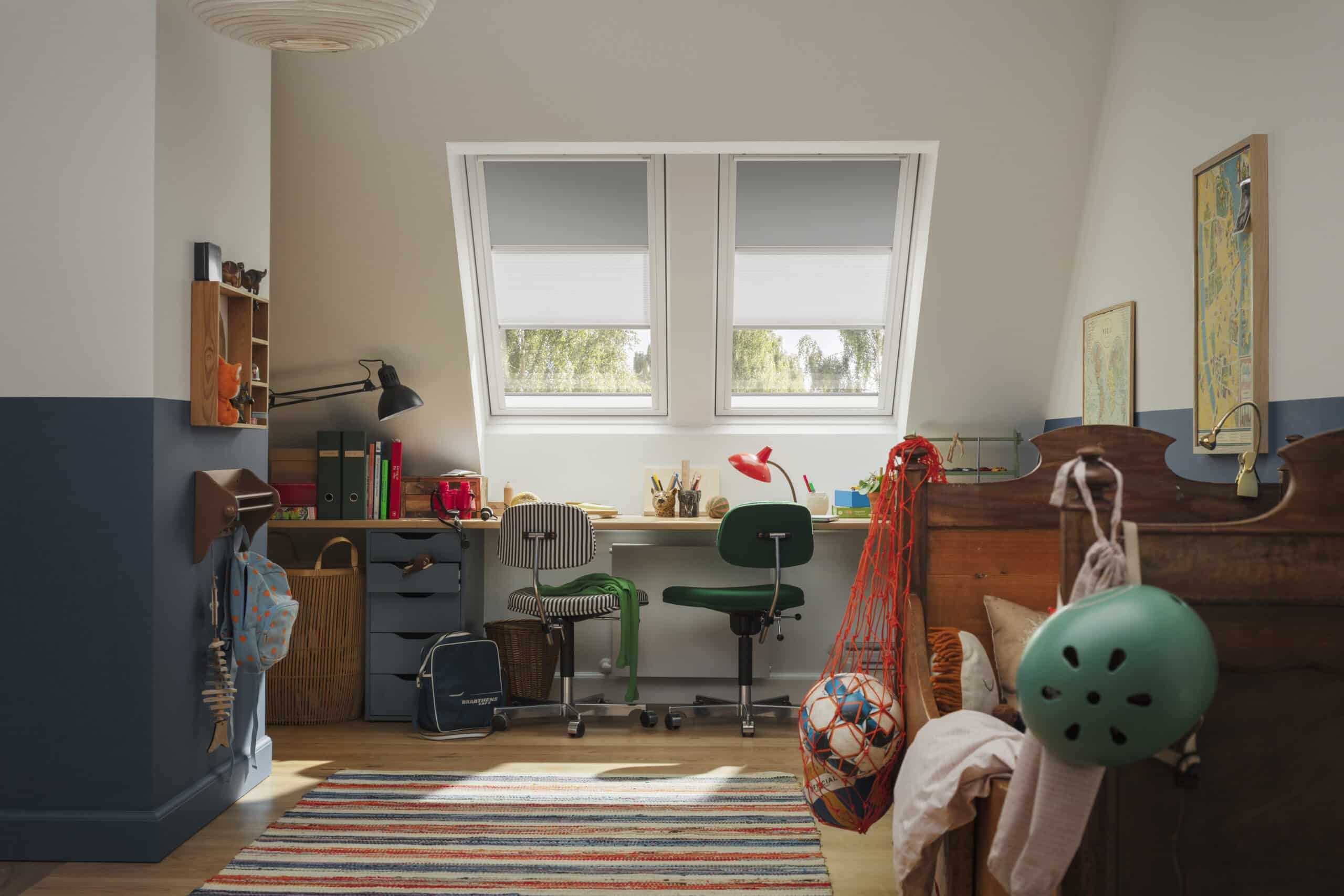 Chambre d'enfant sous les combles avec plafond en pente et fen&ecirc;tres de toit VELUX, d&eacute;coration color&eacute;e.