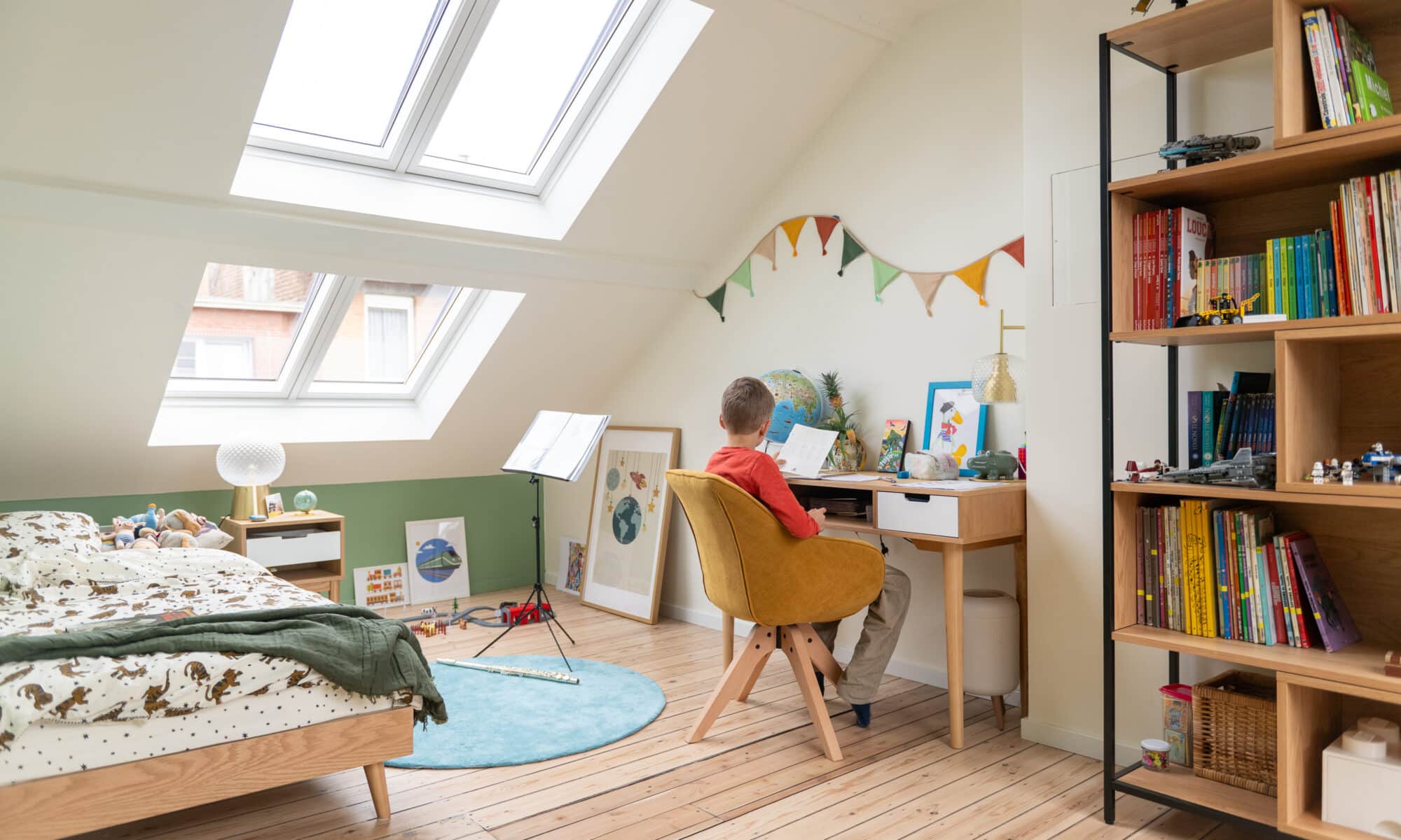 Chambre d'enfant sous les combles avec coin bureau, plafond en pente, fenêtres de toit VELUX.