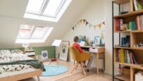 Chambre d'enfant sous les combles avec coin bureau, plafond en pente, fenêtres de toit VELUX.